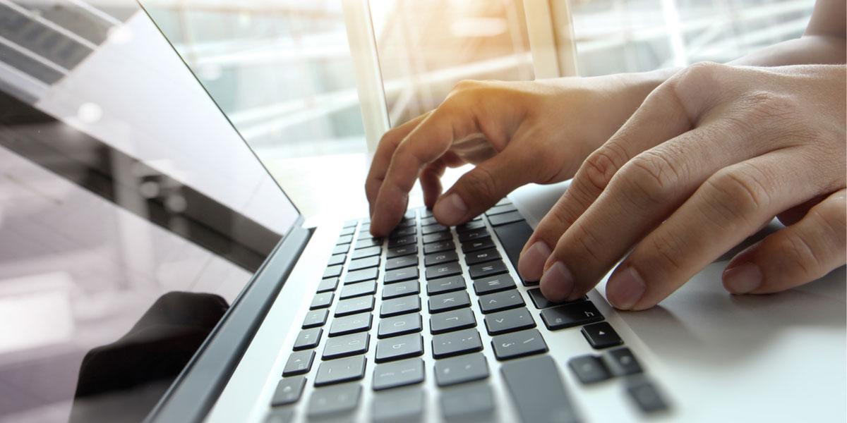 Hands typing on laptop keyboard.